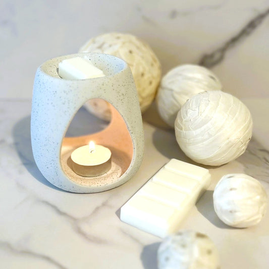 Linen Air wax melt burning in a minimalist ceramic burner on a marble surface