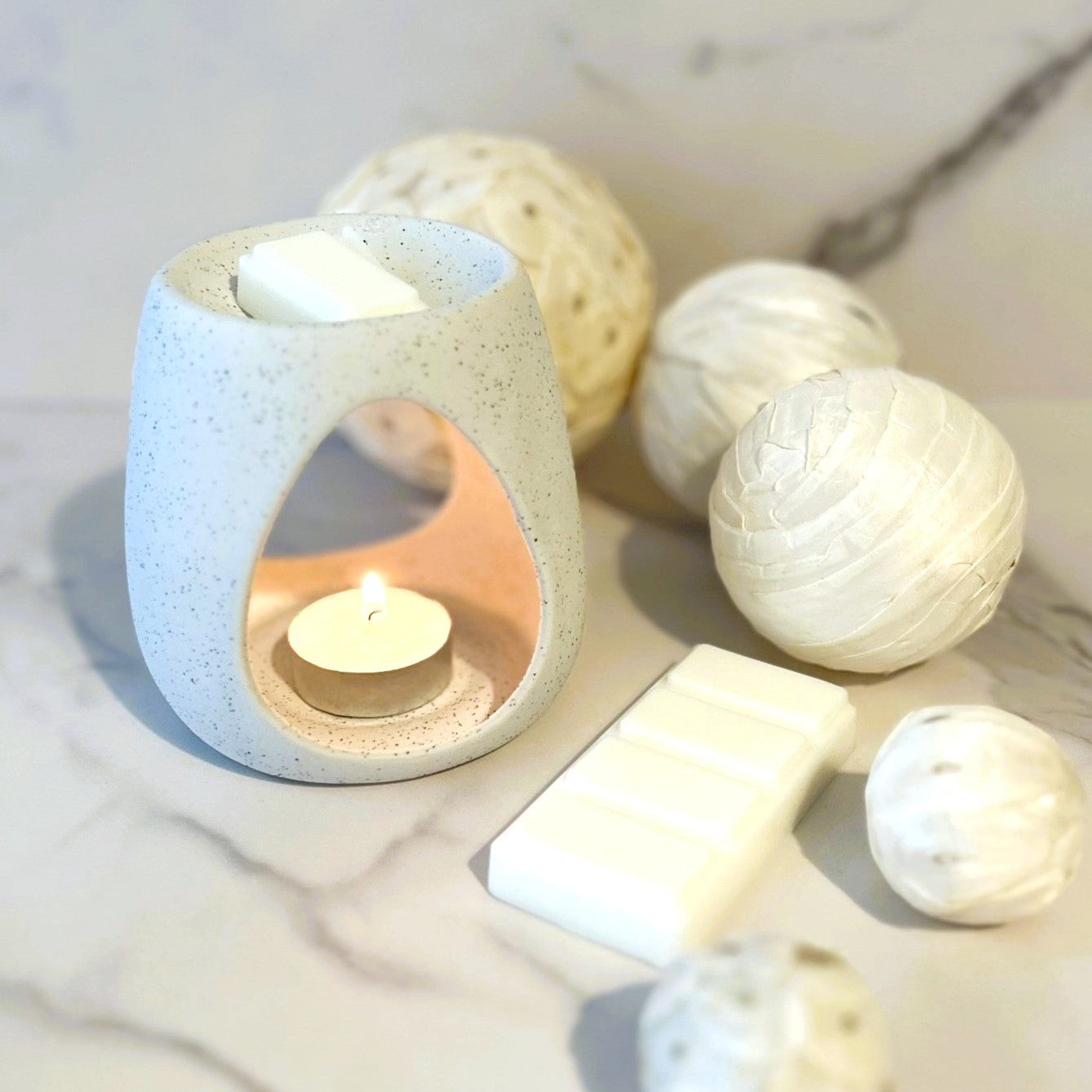 Linen Air wax melt burning in a minimalist ceramic burner on a marble surface