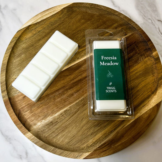 Freesia and pear spring wax melts on wooden tray with packaging and snap bar.
