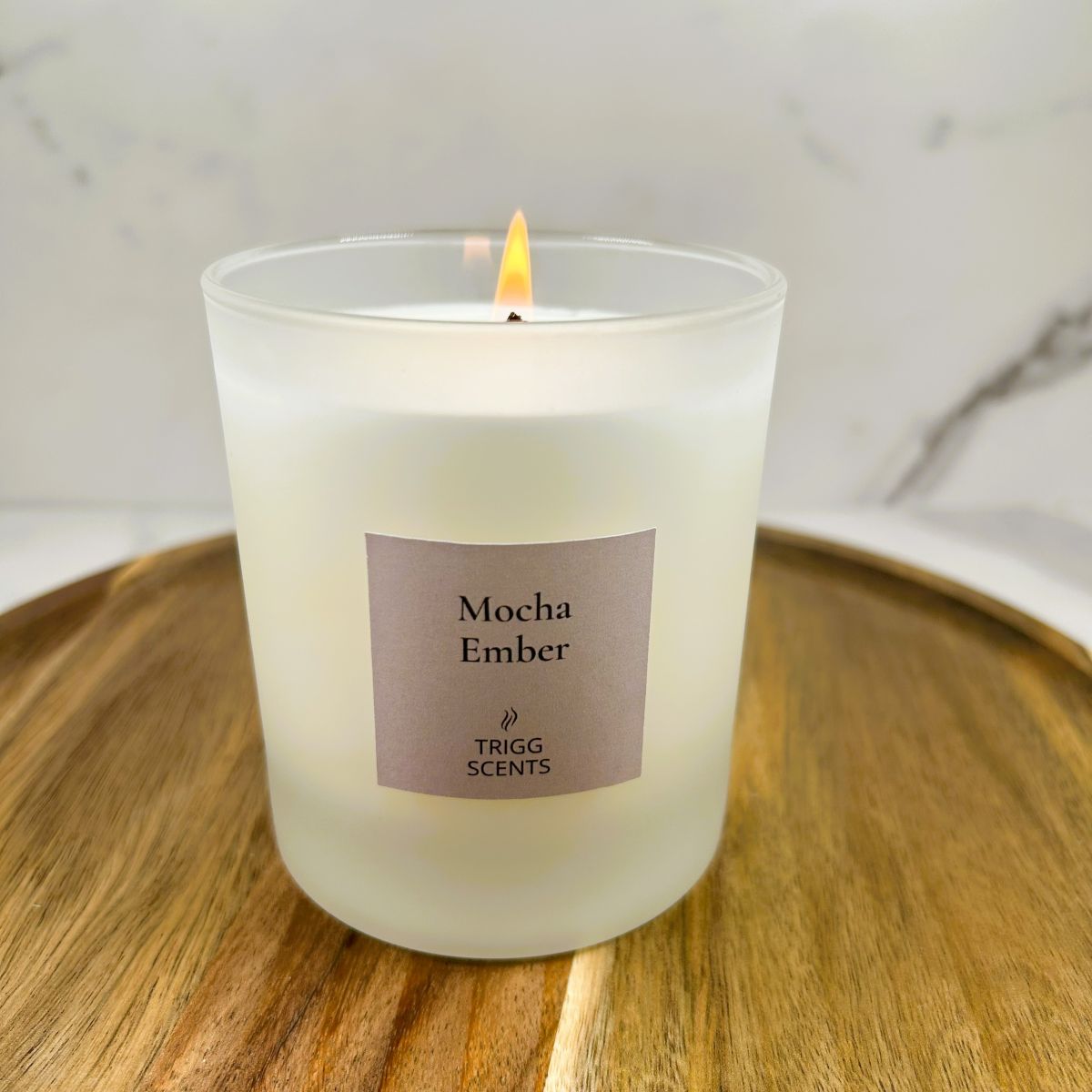 Mocha Ember scented candle glowing with coffee and cocoa fragrance on wooden tray.